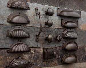 Collection of aged brass cabinet handles and knobs in a Bronze finish on a wooden surface